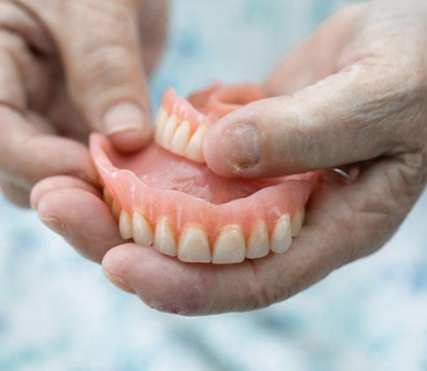 two elderly hands holding a set of dentures